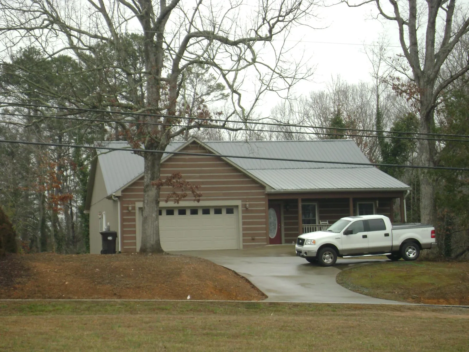 Gray metal roof on a log sided house with an attached two car garage in Bowling Green