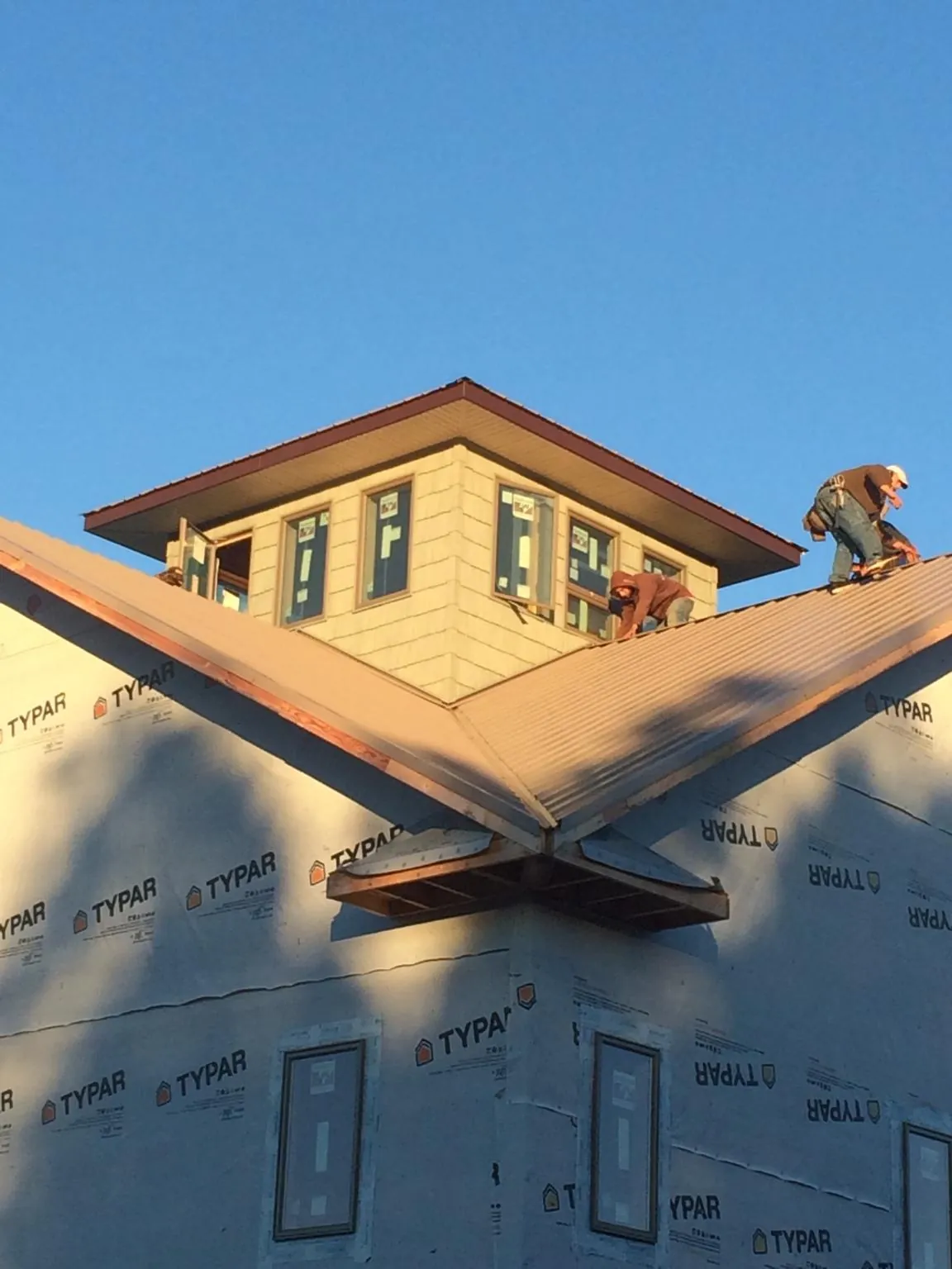 Roofers working around a rooftop cupola on a new metal roof at sunset — Roof Waterproofing in Bowling Green by Roofing Brothers